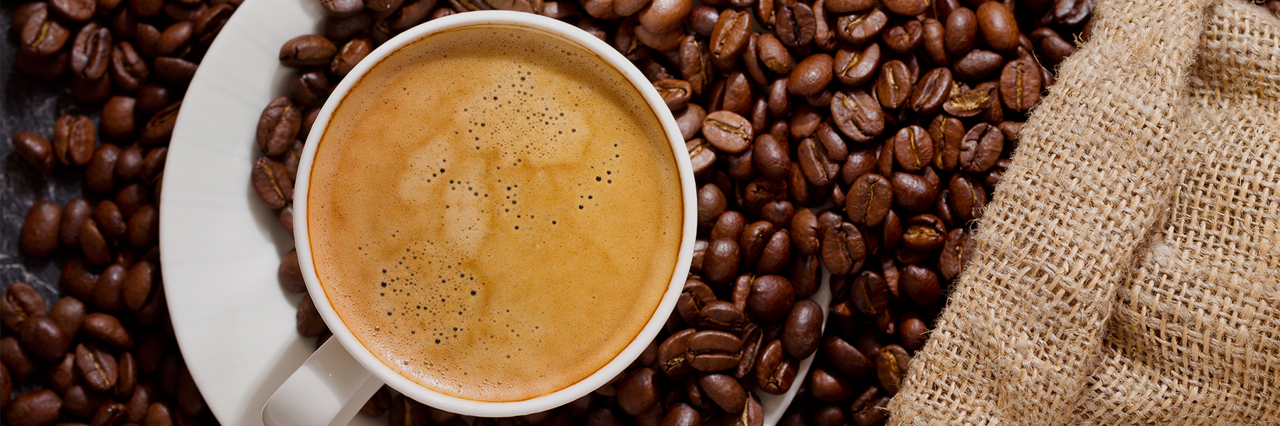 Hot cup of coffee among beans fortified with an added serving of the Nurolift dry lions mane mushroom powder